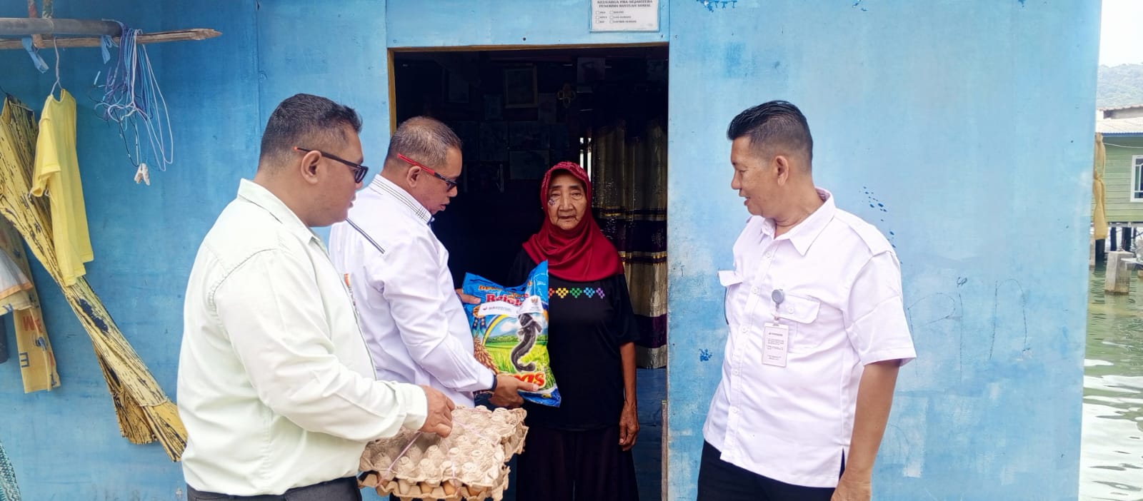 Kepala Bank Riau Kepri Syariah Cabang Anambas saat serahkan sembako ke warga di dampingi Staf.