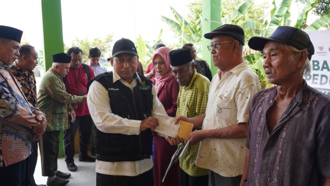 Pimpinan BAZNAS Kota Batam, Wakil Ketua II Bidang Pendistribusian dan Pendayagunaan H. Muhith, M.Ag. menyerahkan bantuan kepada warga.