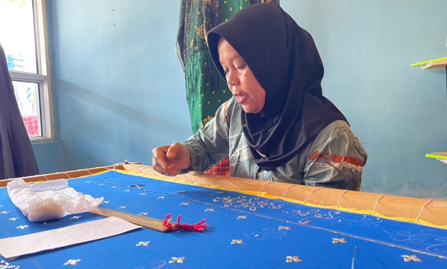 Leni, Pengrajin Tudung Manto sedang asyik menyulam merangkai motif di sehelai kain agar menjadi tudung manto yang cantik, elegan, mewah tanpa meninggalkan khasanah budaya Melayu.